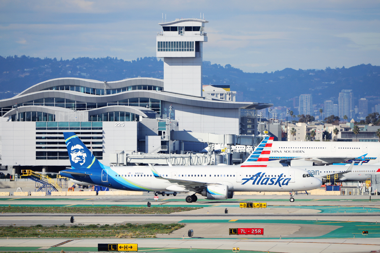 An Alaska Airlines plane on a busy runway in front of an American Airlines jet